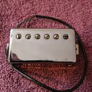 Stříbrný humbucker s chromovaným krytem a šesti viditelnými šrouby. Z nástroje vedou červený, zelený a černý vodič. Povrch krytu vykazuje drobné škrá…