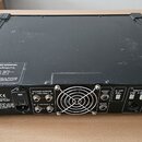 Černý zesilovač v transportním kufru s kovovými hranami. Na zadním panelu jsou nápisy Hartke Systems, SPEAKER OUTPUTS (HIGH FREQ a LOW FREQ), EFFECT…