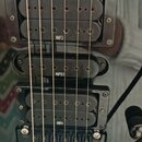 Detail elektrické kytary s černým povrchem a třemi snímači. Horní a spodní snímač jsou typu humbucker s nápisy INF3 a INF4, prostřední je jednoduchý…