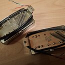 Dvě elektrické snímače typu humbucker z pohledu základní desky. Obě mají stříbrný kovový kryt a na spodní straně je vyražen nápis Gibson USA. Jsou vi…