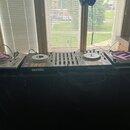 Sada DJského vybavení složená z mixeru s dvěma kontrolérymi a dvou turntable. Středový přístroj nese nápisy serato a Pioneer Dj. Po obou stranách jso…