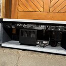 Zadní strana kytarového komba s bílým povrchem z vinylu a černými hranami. Na zadním panelu je nápis ValveKing VK 100v a logo Peavey. Jsou zde vidite…