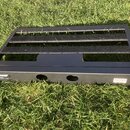 Černý kovový pedalboard s mřížkovým povrchem a dvěma vodorovnými lištami. Na levé straně spodní lišty je viditelný nápis „S-270“. Na pravé straně spo…