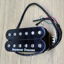 Černý humbucker s kovovým krytem a dvěma řadami magnetických pólů. Na spodní části je bílý nápis Seymour Duncan. Povrch krytu vykazuje drobné škrában…