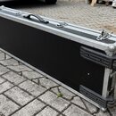 Černý obdélníkový kufr z materiálu připomínajícího textil nebo vinyl s hliníkovým profilem po obvodu. Má jednu černou plastovou rukojeť nahoře, tři k…