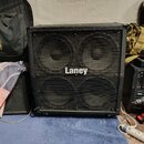 Černý basový reproduktor s kovovou mřížkou, za kterou jsou vidět čtyři velké membrány. Uprostřed mřížky je bílý nápis Laney. Povrch je v dobrém stavu…