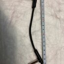 Černý propojovací kabel s dvěma 6,3mm jack konektory. Vedle kabelu je přiložen bílý krejčovský metr, který ukazuje délku kabelu přibližně 17 cm. Povr…