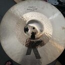 Stříbrný kovový činel s viditelným kovánívým povrchem a důlky v oblasti zvonu. Na povrchu je černý nápis „Custom Hybrid Crash 18"“. V dolní části okr…