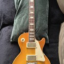 Elektrická kytara s žlutým gradientním lakem a bílým plechtrzem. Na hlavě hředu je viditelné logo Gibson. Nástroj má dva humbuckery, čtyři ovládací k…