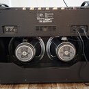 Zadní strana černého kytarového komba s dvěma reproduktory. Na obou reproduktorech je bílý štítek s nápisy CELESTION LOUDSPEAKERS, G12 65 a CELESTION…