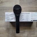 Černý dynamický mikrofon s mřížkou, na těle kterého je bílý nápis AUDIX a pod ním označení OM3. Mikrofon leží na bílém papírovém podkladu s technický…
