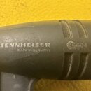Detailní pohled na černý mikrofon z plastu nebo kovu. Na těle je bílý nápis SENNHEISER s logem a pod ním text MADE IN GERMANY. Vpravo je vidět vybled…