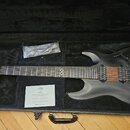 Černá elektrická kytara v otevřeném černém kufru. Na hlavě je logo CHAPMAN GUITARS a na hrazence symbol nekonečna. Tělo kytary je matně černé s vidit…