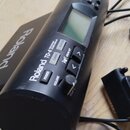 Černý elektronický bicí modul značky Roland, model TD-4. Na přední straně jsou tlačítka s nápisy POWER, VOLUME, TUNING, MUFFLING a DRUM KIT, dále mal…
