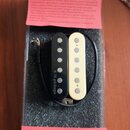 V plastovém obalu na černém molitanu jsou dva kytarové snímače typu humbucker, jeden v černé a druhý v krémové barvě. Na černém snímači je svisle nap…