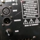 Detail zadní strany černého elektronického zařízení s ovládacími prvky. Jsou zde vidět konektory s popisky INPUT a THROUGH, přepínač GROUND ON / LIFT…
