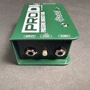 Zelený kovový box s nápisy PRODI a PASSIVE DIRECT BOX. Na horní straně je logo Radial engineering a přepínač s označením -15dB PAD. Přední strana obs…