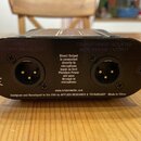 Zadní strana černého elektronického zařízení s dvěma XLR konektory. Nad levým konektorem je nápis DIRECT MICROPHONE OUTPUT a nad pravým TRANSFORMER I…