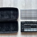 Na fotografii je černá groovebox s nápisy Roland a GROOVEBOX MC-101. Zařízení obsahuje několik ovládacích knofíků, tlačítka a bílé posuvníky. Součást…