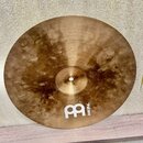 Kruhový mosazný činel s viditelným broušením povrchu. V dolní části je bílé logo a nápis MEINL. Povrch vykazuje tmavší, nepravidelné skvrny a oxidaci.