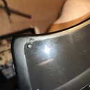 Detailní záběr na černý, pravděpodobně plastový nebo lakovaný povrch hudebního nástroje či příslušenství. Povrch je v horní části výrazně odepsaný a…