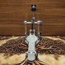 Stříbrný kovový pedál basového bubne s černým knoflíkem nahoře. Na spodní části pedálu je vyryto logo SONOR. Nástroj vykazuje mírné známky používání…
