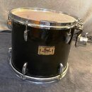 Černý buben s chromovaným kováním a bílým blánou. Na korpusu je zlatý štítek s nápisy Pearl, Masters Studio a pod nimi menší text MADE IN TAIWAN. Pov…