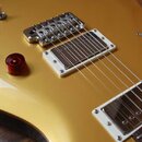 Detail elektrické kytary v žlutém lesklém provedení. Nástroj má dva humbuckery s bílými rámečky, stříbrný kobylník a tři červené oválné ovládací knof…