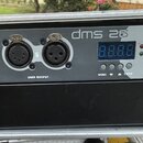 Šedý rackový kontrolér s nápisem dms 26 a logem BriteQ. Zařízení má čtyři konektory XLR, u kterých jsou nápisy DMX OUTPUT a čísla 5 a 6. V pravé část…