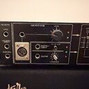 Černý elektronický přístroj s ovládacími prvky. Na panelu jsou nápisy REMOTE, MICROPHONE, LEVEL, LOW a VOICE CHARACTE. Viditelné jsou vstupy označené…