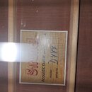 Fotografie zachycuje vnitřní štít akustické kytary. Na štítu je červeným svislým písmem nápis Strunel a černý text Acoustic Guitar Made in [nečitelné…