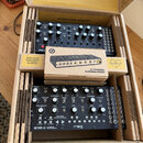 V kartónovém boxu jsou dva černé syntezizátory a jeden malý mixér v krabičce. Horní přístroj má nápis DFAM, spodní nápisy MOTHER-32 SEMI MODULAR ANAL…