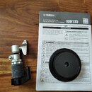 Fotografie zobrazuje uživatelský manuál a součástku elektronického bubnu. Na šedém papíře je nápis YAMAHA, ELECTRONIC DRUM PAD / PAD DE BATTERIE ÉLEC…