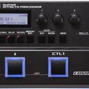 Černý kytarový procesor s nápisem BOSS GT-1 GUITAR EFFECTS PROCESSOR. Zařízení obsahuje displej s textem BOSS GT-1, tři ovládací knoflíky, řadu tlačí…