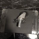 Kolečko z kovu a plastu v originálním plastovém obalu. Na šedém kartonu pod ním je vidět část nápisu LOOR a grafický symbol připomínající sloupce equ…