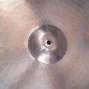 Kruhová kovová činely v stříbrné barvě s koncentrickým žebrováním. Na povrchu je viditelné logo Zildjian a v pravé části jsou hnědé skvrny od oxidace…