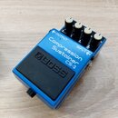 Modrý efekt pedál značky BOSS s nápisem Compression Sustainer CS-3. Na horní straně jsou čtyři bílé ovládací knoflíky a označení OUTPUT a INPUT se ši…
