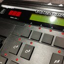 Černý elektronický přístroj s nápisem VOCALIST VHM5 a logem Digitech. Zařízení má zelený LCD displej, červené kontrolní LED diody a několik černých t…