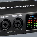Černý audio rozhraní s modrými bočními panely. Na přední straně jsou nápisy PreSonus a STUDIO 24 c, dva kombinované konektory s označením 1 a 2 a pop…