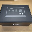 Černá krabice s produktovou fotografií audio rozhraní. Na horní části je vidět nápis AUDIENT a označení modelu iD14. Na přední straně krabice je bílý…