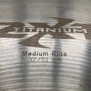 Detailní záběr na povrch kovového činely. Je na něm vidět nápis TITANIUM v rámci velkého loga ZKT a text Medium Ride 20"/51 cm. Povrch vykazuje jemné…