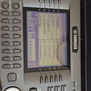 Detailní pohled na ovládací panel stříbrného digitálního klavíru značky YAMAHA. Uprostřed je LCD displej zobrazující seznam zvuků v sekci VOICE (MAIN…