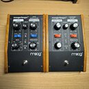 Dvě efektové pedály Moog v černém provedení s dřevěnými bočními panely. Levý pedál nese nápisy moogerfooger RING MODULATOR a logo moog, pravý pedál n…