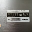 Fotografie detailu štítku na stříbrném kovovém povrchu. Na štítku je uveden název NANO LEGACY FLOOR a popis Portable Dual Channel Floor Amplifier. Js…