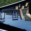 Detail elektrické kytary s černým lakem a zlatými komponenty. Na hmatníku jsou dva humbuckery, přičemž na zadním je nápis Seymour Duncan. Kytara má z…