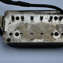Kytarový humbucker s kovovým krytem a dvěma montážními pružinami po stranách. Na povrchu krytu je vyryté logo Gibson, materiál vykazuje výrazné známk…