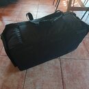 Černá transportní taška z textilního materiálu s několika úchopy. Na povrchu nejsou viditelné žádné značky ani nápisy. Taška je v dobrém stavu bez vi…