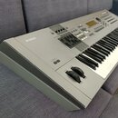 Šedý elektronický klavír značky YAMAHA. Nástroj má ovládací panel s displejem, několika posuvníky a tlačítky. Na levé straně je viditelné logo YAMAHA…