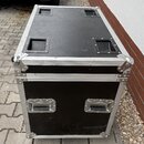 Černý transportní kufr s hliníkovými hranami a kovovými rohy. Horní strana má čtyři zapuštěné úchopy, přední strana dva vnější kovové úchyty. Povrch…