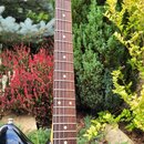 Elektrická kytara s černým bodies a hnědým hmatníkem. Na hlavě je viditelné logo Fender Stratocaster. Povrch laku na těle vykazuje drobné škrábance a…